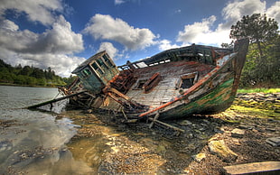wrecked brown and green boat under cloudy blue sky during daytime
