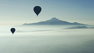 two silhouette of hot air balloons flying on sky with overlooking view coned mountain at daytime HD wallpaper
