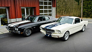 two black and white coupes beside red building at daytime HD wallpaper