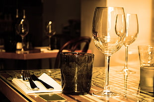 depth of field photography of black glass beside clear glass wine glass on top of table