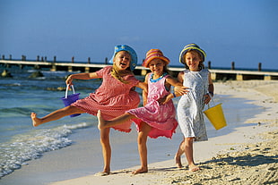 three girls standing beside seashore