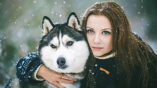 woman wearing black parka jacket holding Siberian Husky