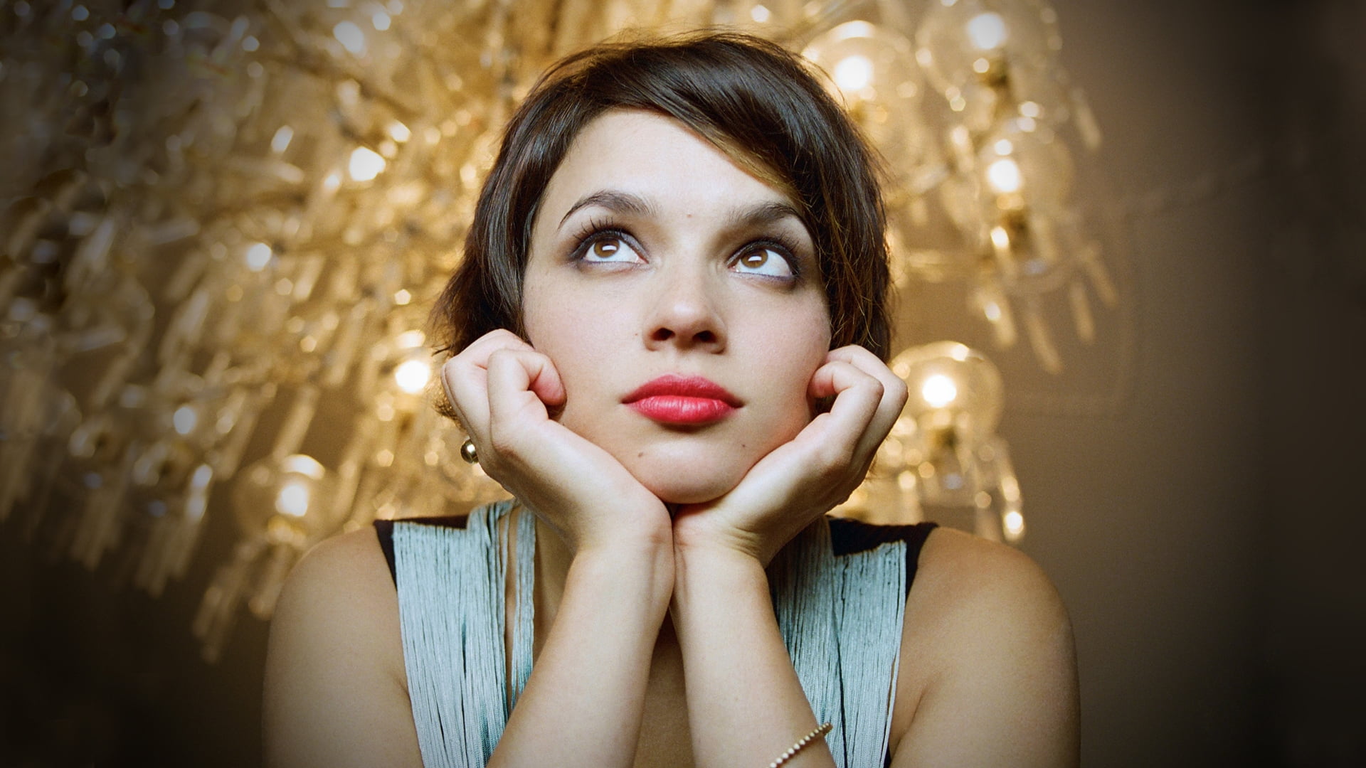 woman in gray and black clothes under gold-colored chandelier