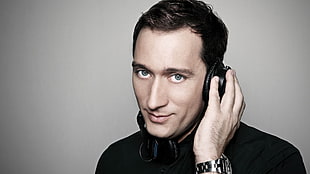 man wearing black headphones beside white wall