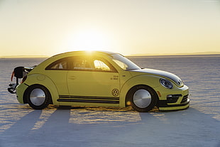 photo of yellow Volkswagen New Beetle on seashore