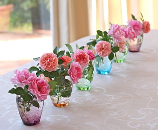 pink Peonies, pink Roses, and pink Carnations in clear glass vases centerpieces