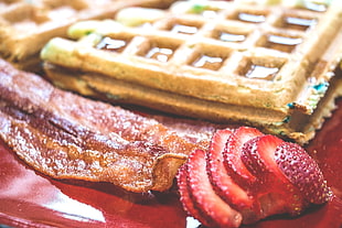 strawberry, bacon, and waffle dish served on red plate