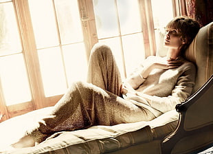 woman in gray sweater lying on brown suede couch