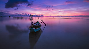 photo of a canoe boat on a body of water under purple skies