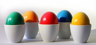 five assorted painted egg on white ceramic vbases