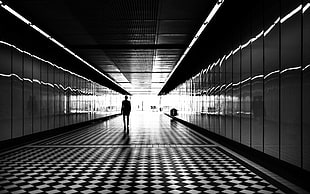 silhouette photo of person walking in enclosed pathway