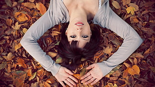woman in gray cardigan lying on brown dried leave
