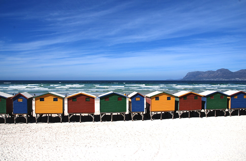 person taking photo of multi-colored mini houses near beach during daytime HD wallpaper