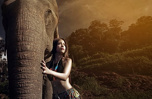 woman wearing black crop top holding elephants trunk
