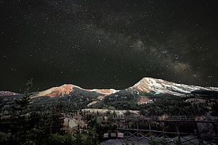 snow field mountain beside green trees under stars, red mountain