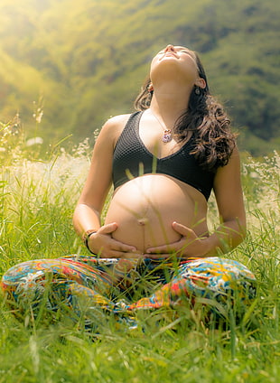 pregnant woman wearing black brassiere and teal pants sitting on green grass field during daytime HD wallpaper