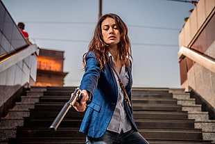 female wearing blue blazer aiming gun with supressor photo