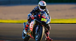 man riding on blue, red and white sports bike while wearing white full-face helmet