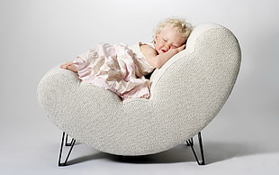 baby girl lying on gray chair
