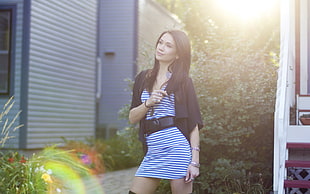 woman wearing black cardigan and white and blue stripe dress standing near on flowers