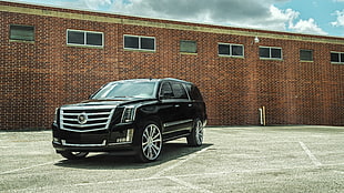 black Cadillac Escalade ESV parked on gray concrete pavement near building during daytime