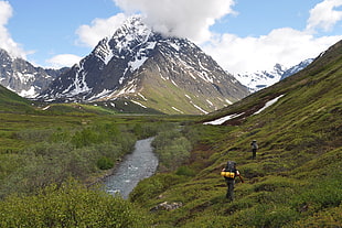 photo of two persons traveling in a mountain during day time, alaska