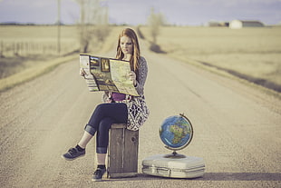 woman's reading near desk globe