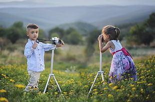 boy and girl taking photo on yellow daisy field