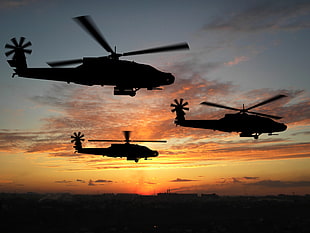 silhouette photo of three helicopters during golden hour