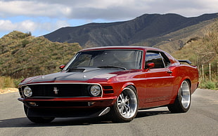 red and black Ford Mustang parked on concrete road with view of mountain