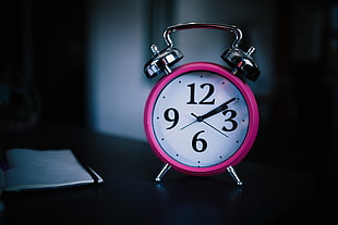 round pink and white analog alarm desk clock