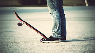 man wearing blue jeans with red skateboard