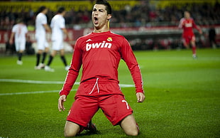 man wearing red Adidas bwin long sleeve shirt and red shorts soccer player standing on green grass field