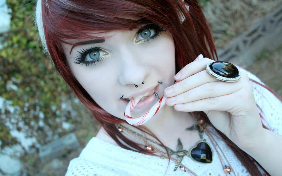 woman biting candy cane near green plant during daytime HD wallpaper