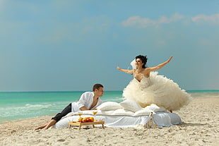 man and woman laying on white bed