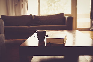 photo of black ceramic mug near book on wooden table