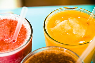 selective focus photo of three clear drinking glasses filled with orange, red, and brown drinks