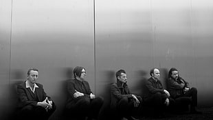 five men sits and leans on wall