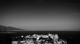 grayscale photography of buildings beside sea