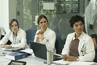 women in white lab coats sitting behind desk