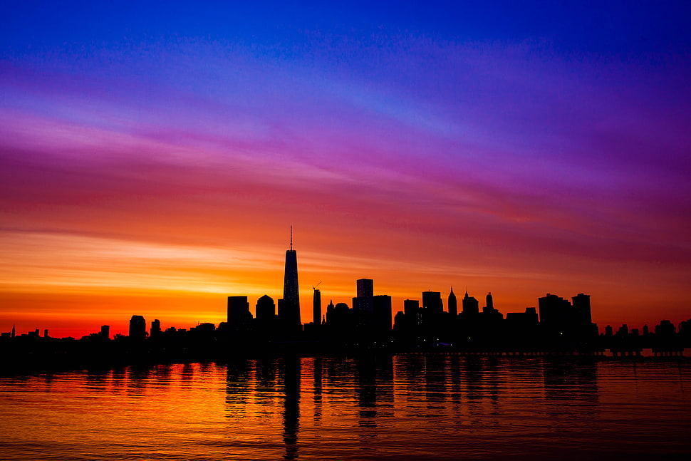 silhouette photo of building under orange and blue skies HD wallpaper