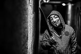 person wearing guy fawkes mask holding bladed weapon