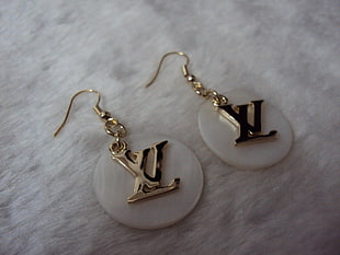 pair of gold Louis Vuitton earrings on round white plastic frames