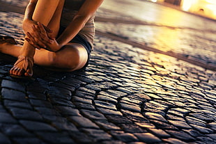 depth of field photography of a person sitting on a bricked ground
