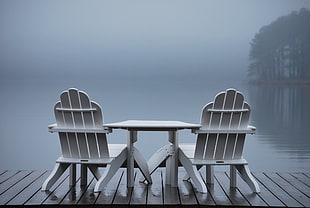 table in between two adirondack chair on dock facing calm waters with mist HD wallpaper