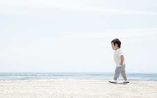 black haired child walking near beach