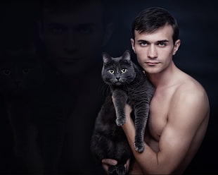 topless man holding black cat
