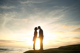 silhouette of man and woman kissing on seashore