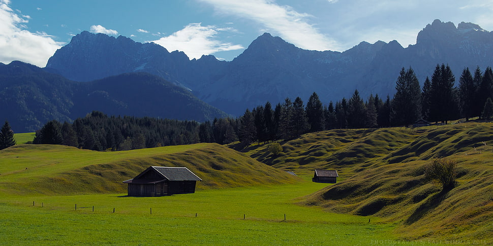 two barns on grass covered hill HD wallpaper