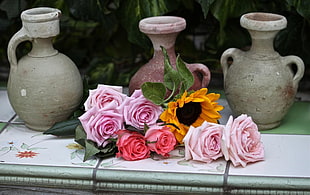 pink roses and sunflowers near three pots